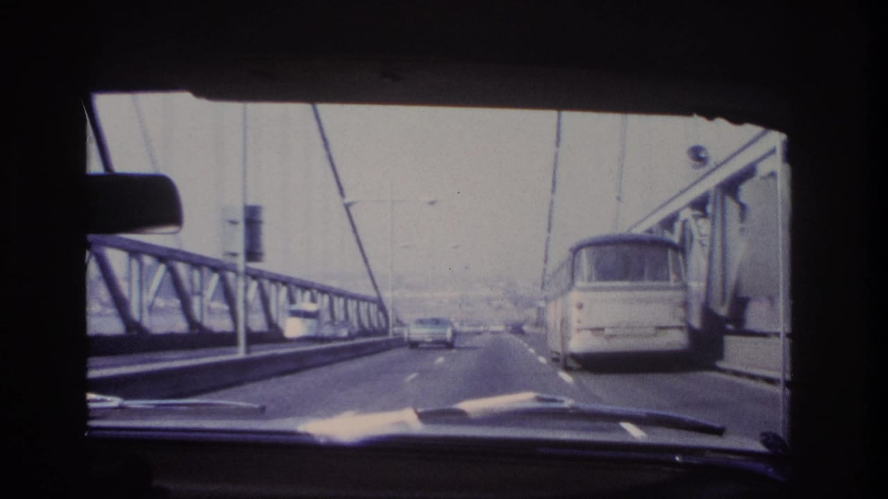 Car-interior view of 1966 bridge traffic near Hoboken, with a bus to the right and cars ahead on the roadway.