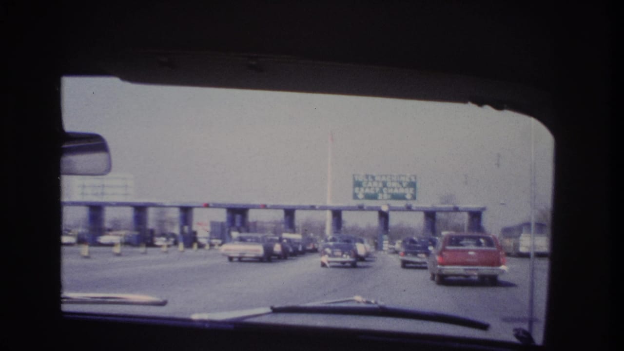 Late clip frame showing traffic near the toll booths in 1966 Hoboken-area road footage, seen through the windshield.