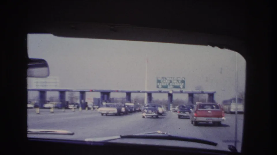 Late clip frame showing traffic near the toll booths in 1966 Hoboken-area road footage, seen through the windshield.