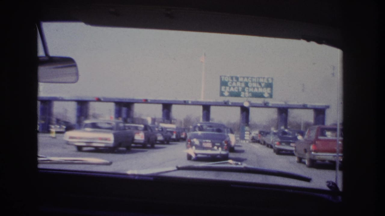 Multiple cars move slowly toward toll booths under an exact-change sign.