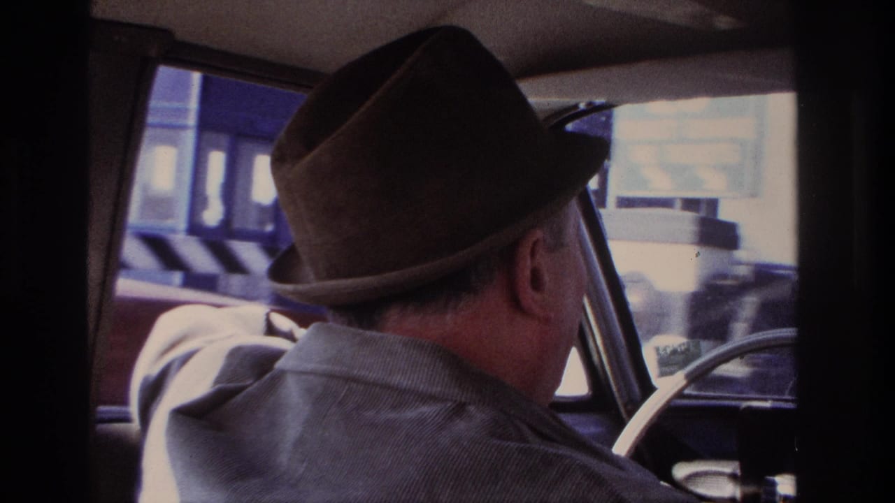 From the rear seat, the home movie records the older driver and bright, blurred Hoboken streetfronts outside the car window.