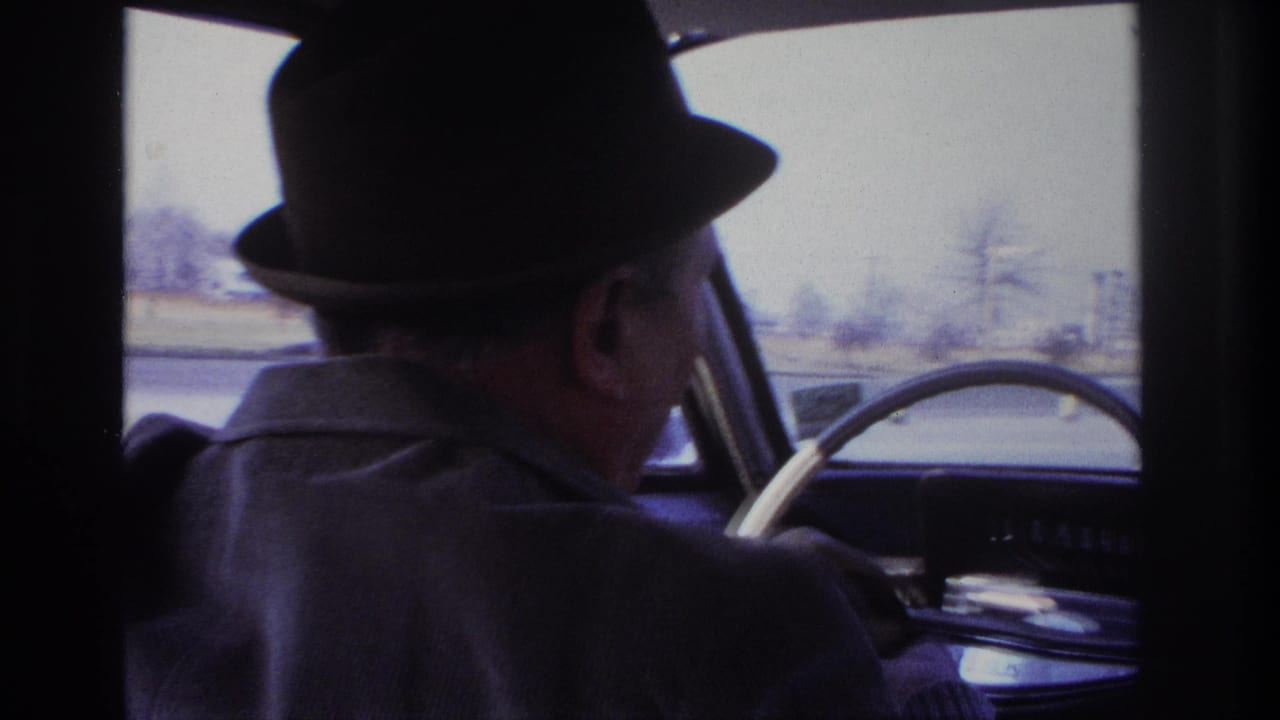 1966 Hoboken home-movie frame with the camera behind the driver, showing the steering wheel and roadside landscape through the windshield.