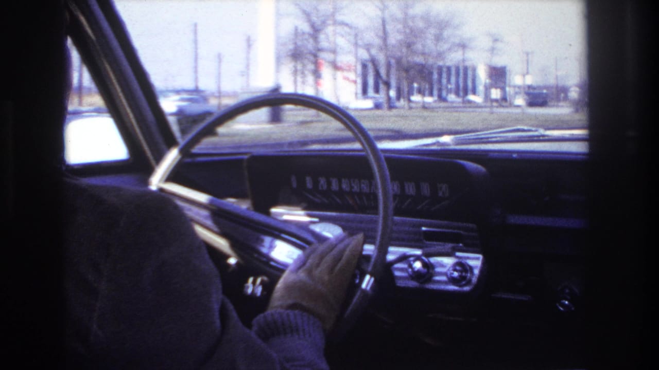 Passenger-seat view of the steering wheel and chrome-trimmed dashboard as the driver continues along a street in Hoboken, New Jersey.