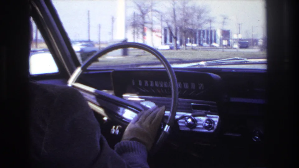Passenger-seat view of the steering wheel and chrome-trimmed dashboard as the driver continues along a street in Hoboken, New Jersey.