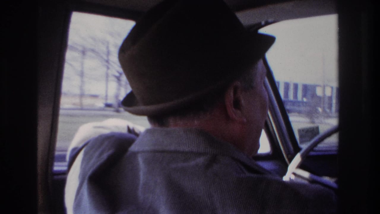 In 1966 Hoboken home-movie footage, a man in a dark fedora is filmed from behind while driving past roadside buildings.
