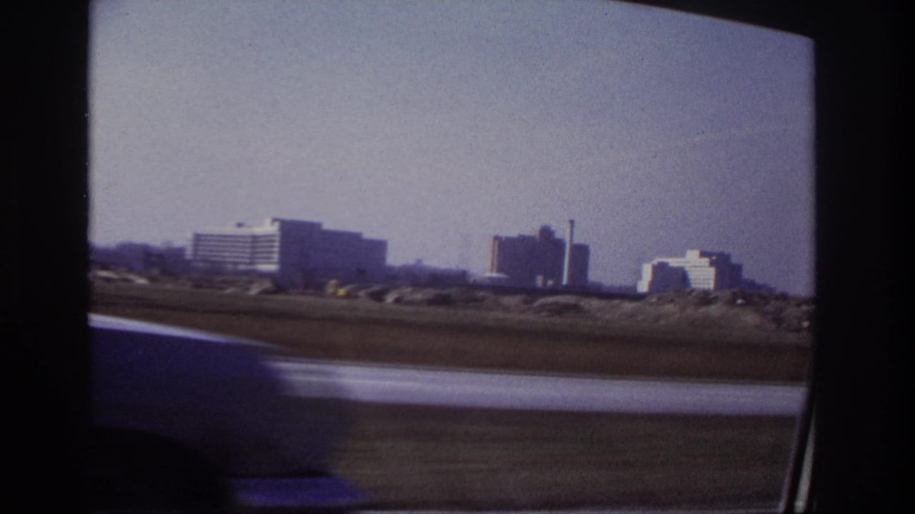 Distant buildings and highway seen through a moving vehicle window.