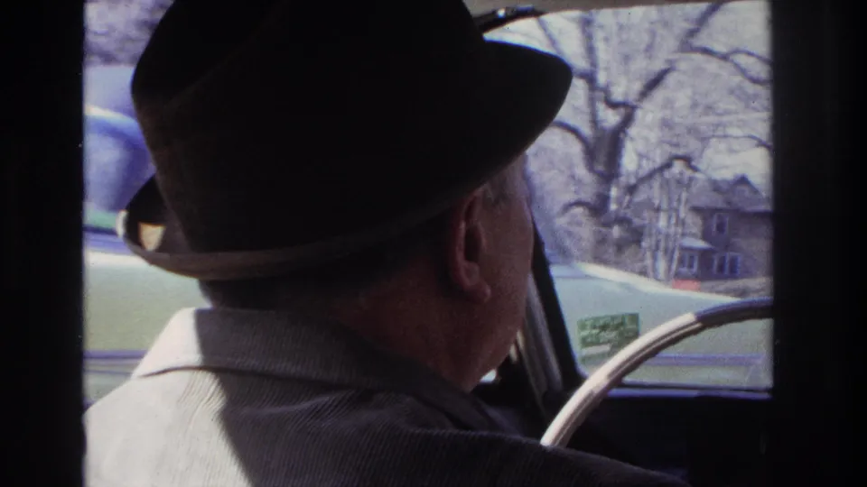 The 1966 Hoboken clip shows the driver from behind, with houses, bare trees, and the car's window frame visible outside.