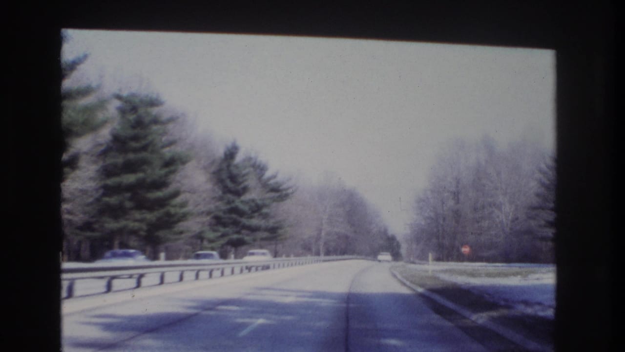 1966 8mm road-trip view near Hoboken, New Jersey, continuing along a wooded roadway after passing the stone bridge.
