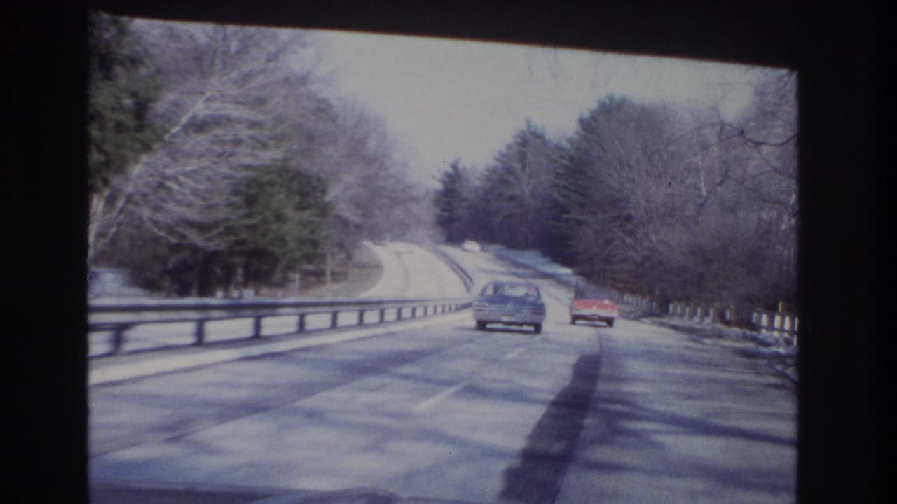 End frame of 1966 8mm driving footage showing two cars ahead on a wooded New Jersey roadway.
