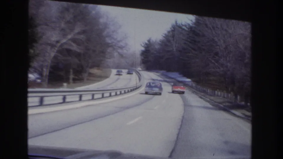 Moving-car view of classic vehicles on a gently curving divided road in the Hoboken, New Jersey metadata context.