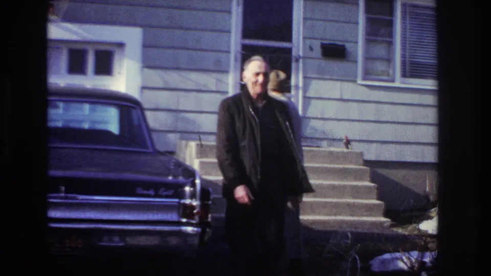 At the end of the supplied Hoboken clip, an older man walks toward the camera with the house steps and dark sedan behind him.