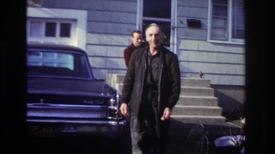 In Hoboken, New Jersey, 1966 home-movie footage, an older man walks near a dark sedan while two men stand by house steps.