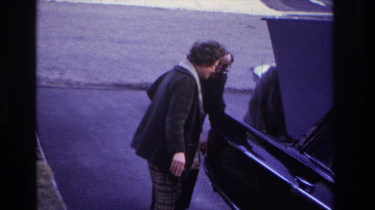 At the end of the 1966 Hoboken clip, the woman stands beside another adult near a dark car, with driveway pavement and snow in view.