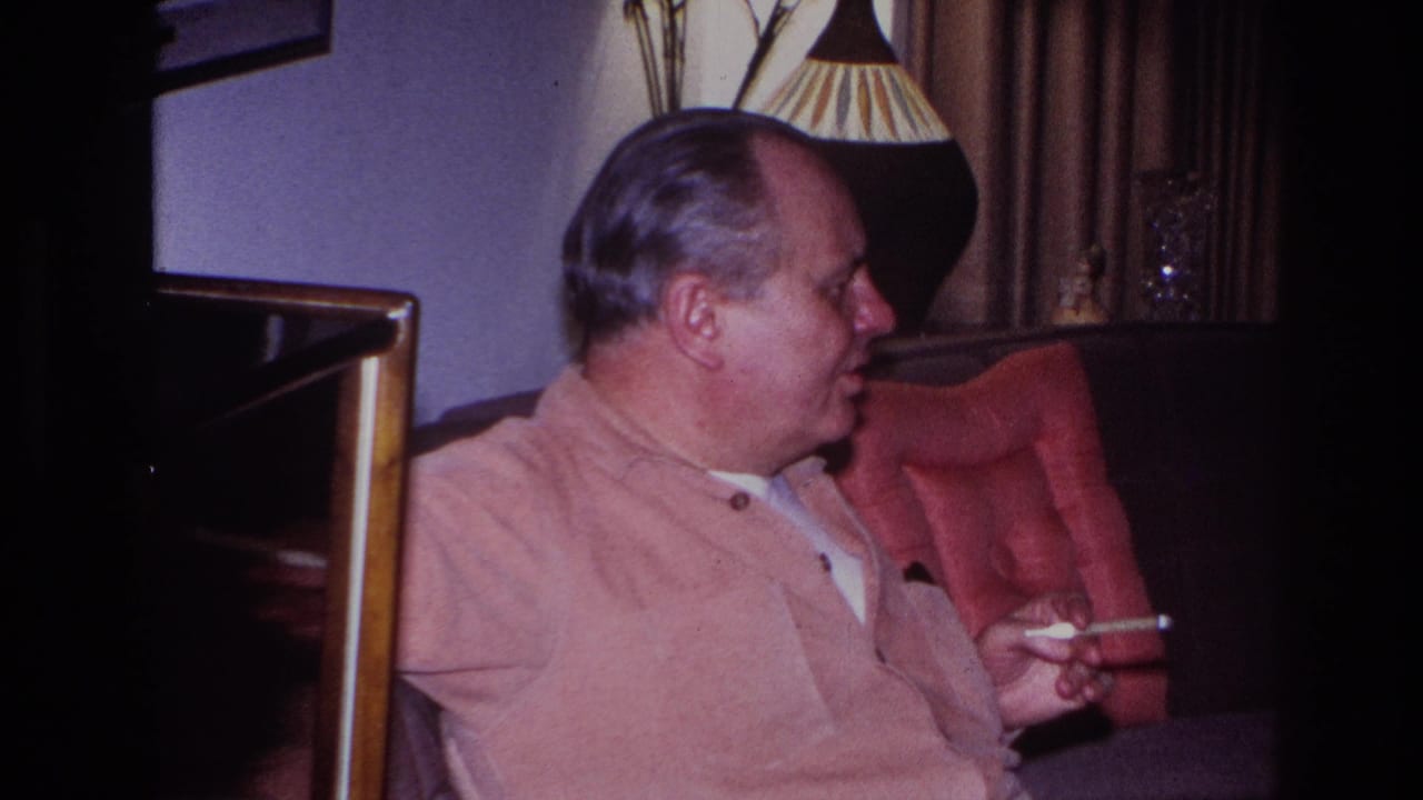 A dim 1966 home-movie frame shows the older man in profile, seated against curtains with a cigarette in hand.
