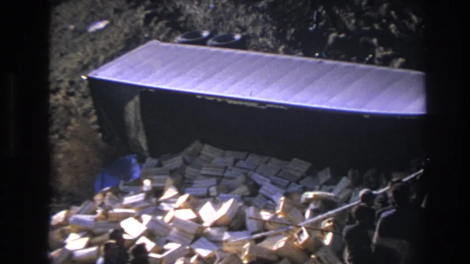 1966 Hoboken frame showing a large metal container with spilled wood blocks, rubble, tires, and rough ground around it.
