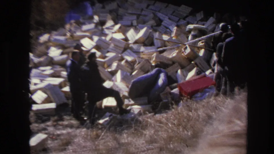Hoboken, New Jersey 1966 home-movie view of men examining a large roadside pile of dumped boxes and debris.