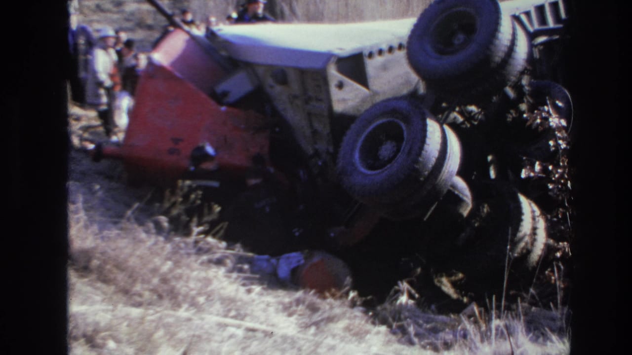 1966 Hoboken accident scene with an overturned car, exposed underside, dry grass, and bystanders partly visible behind it.