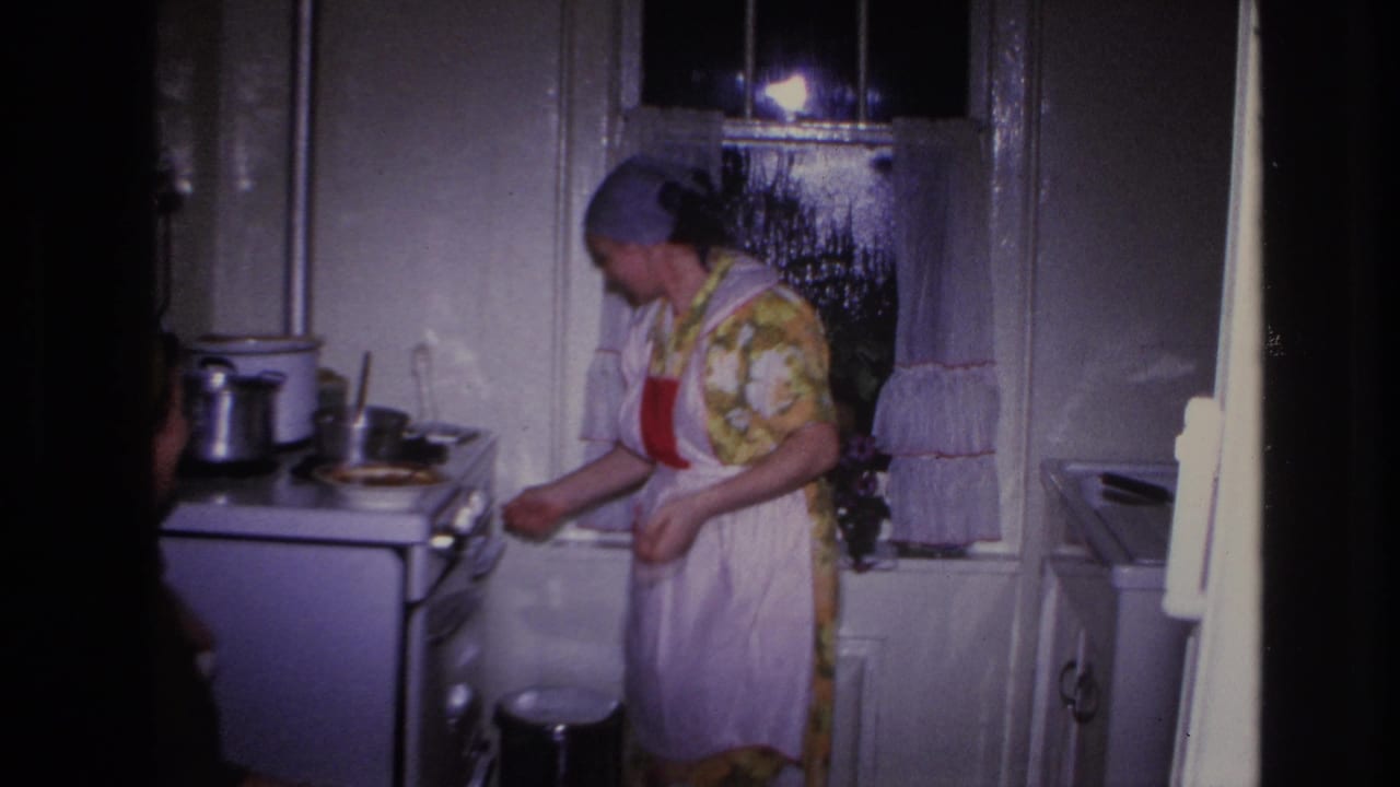 Woman reaching toward stove controls in a small kitchen.