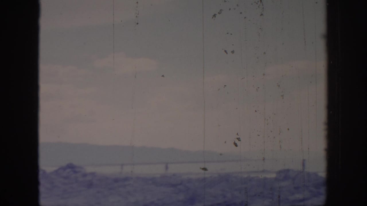 1966 8mm Sacramento-area home-movie view of cloudy sky, distant ridge, water, and dark window framing with visible film wear.
