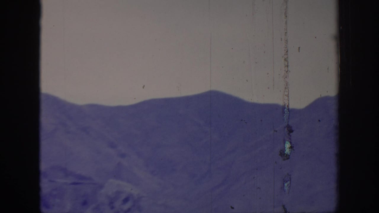 1966 8mm frame labeled Sacramento, California, showing a distant purple mountain ridge with pale sky, rounded frame edges, and vertical film wear.