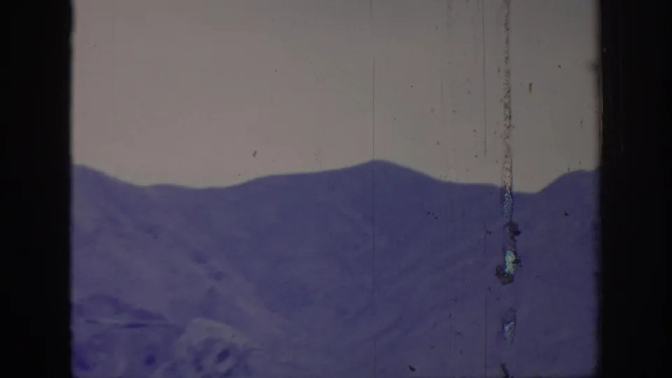 1966 8mm frame labeled Sacramento, California, showing a distant purple mountain ridge with pale sky, rounded frame edges, and vertical film wear.