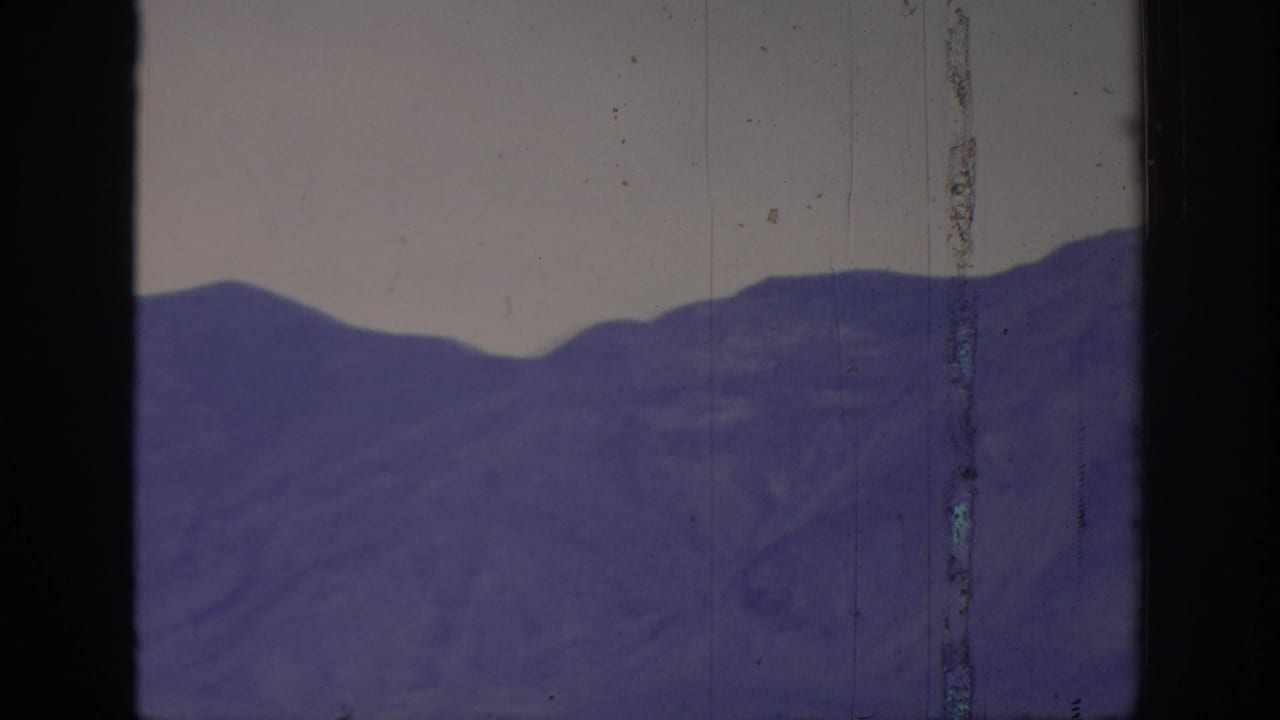 1966 8mm home-movie frame labeled Sacramento, California, with a purple mountain ridgeline, pale sky, and prominent vertical film damage.