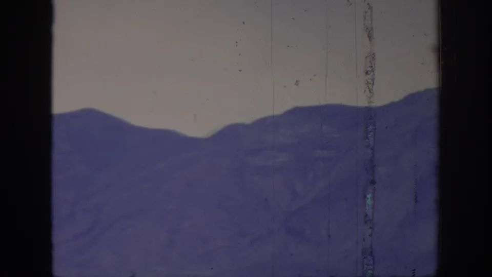 1966 8mm home-movie frame labeled Sacramento, California, with a purple mountain ridgeline, pale sky, and prominent vertical film damage.