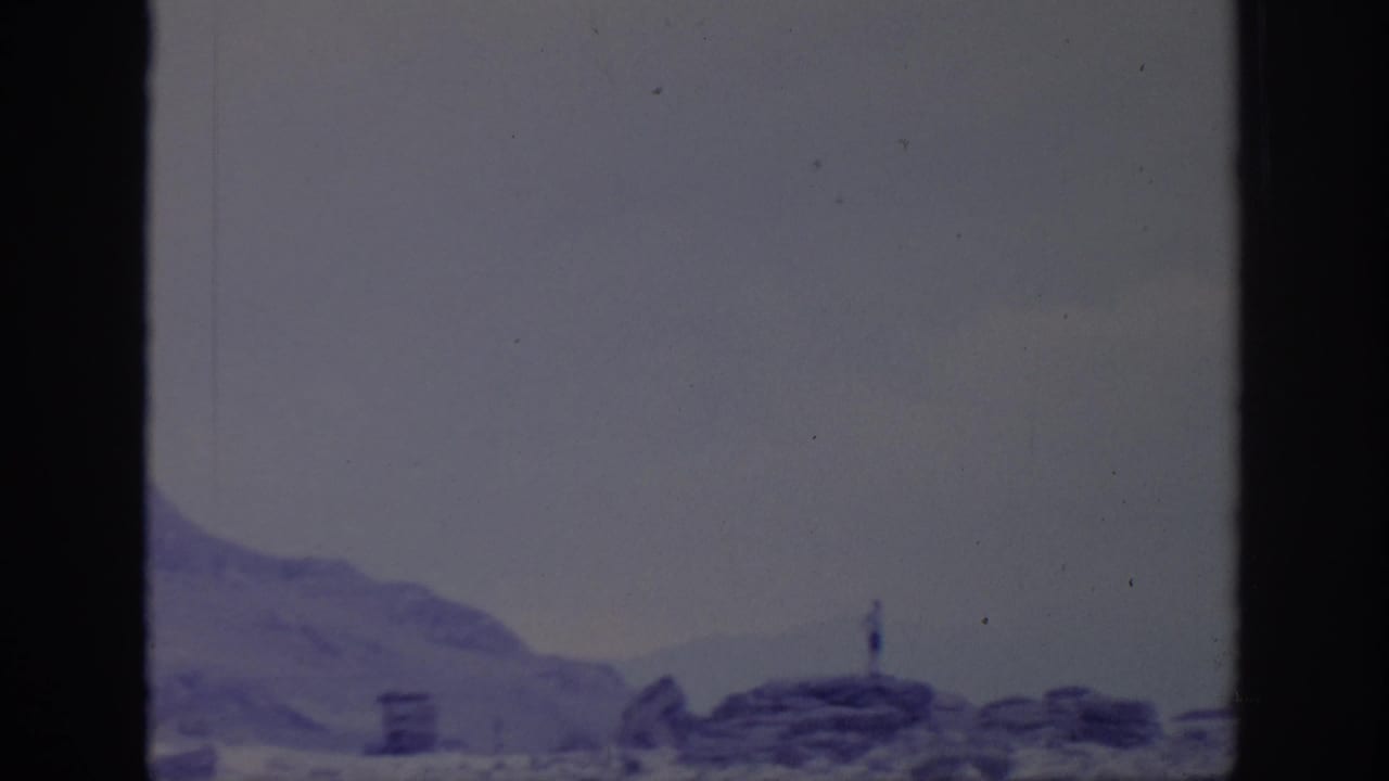 Rocky ridge and distant water seen through dark 8mm frame borders.