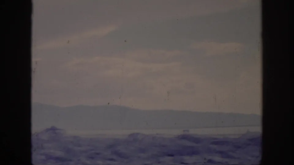 1966 Sacramento-area 8mm frame showing rugged terrain, a pale inlet or waterway, distant hills, and visible film wear.