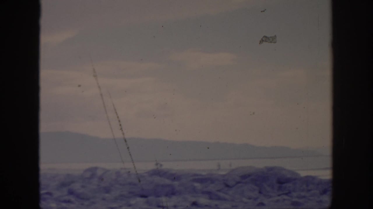 1966 Sacramento-area home-movie frame showing a hazy mountain view beyond a dark window or film border.