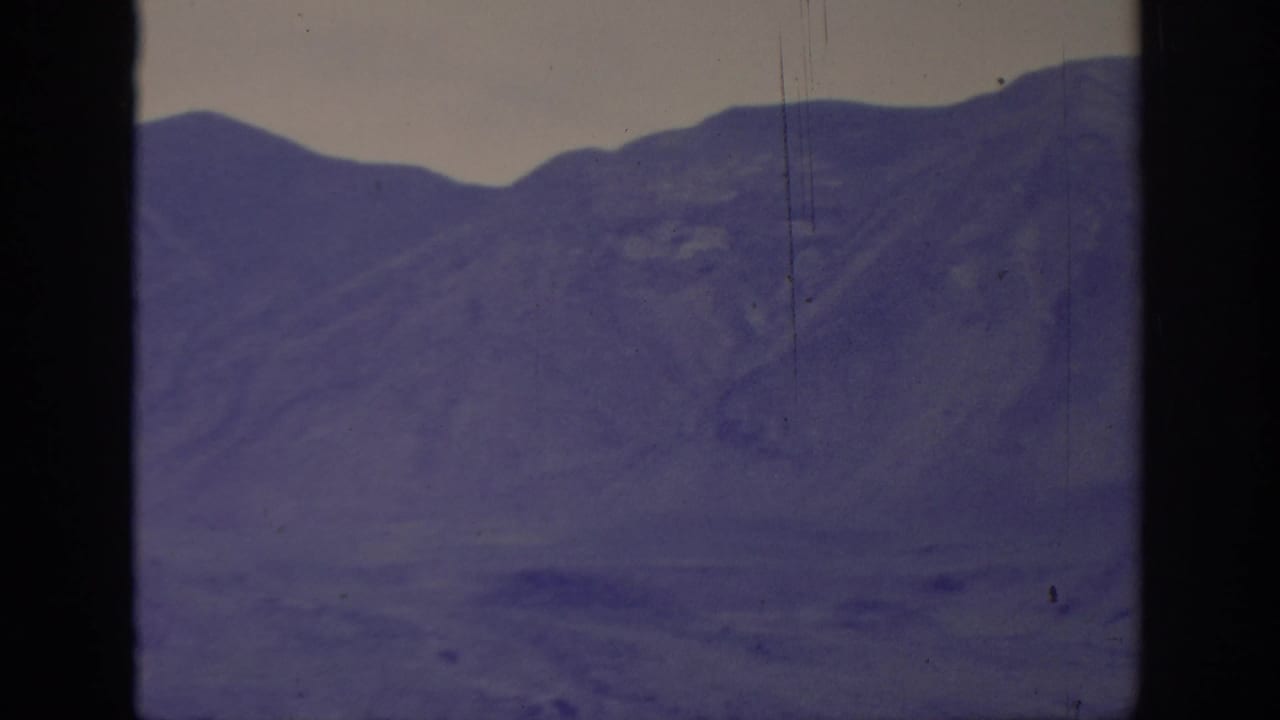 Soft 8mm view of blue-toned mountains near Sacramento, framed by dark film or window edges.