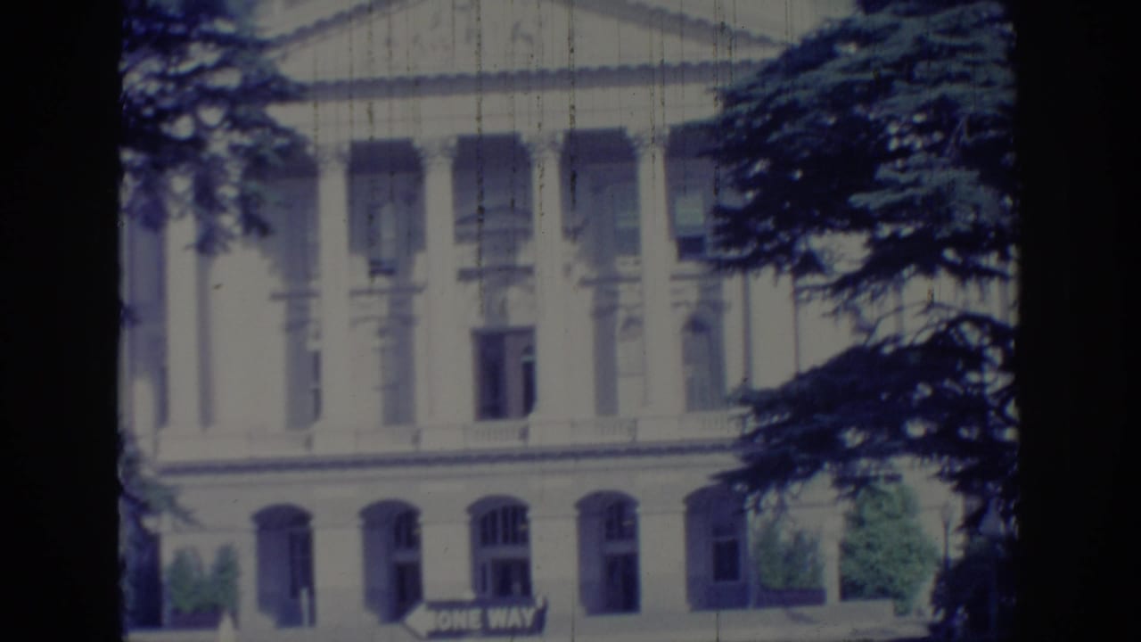 1966 Sacramento view of the California State Capitol exterior, with columns, arched windows, tree branches, and a ONE WAY sign.