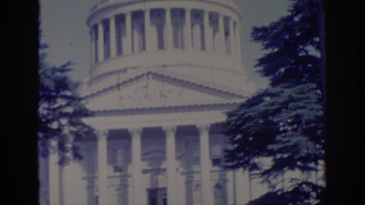 1966 8mm view of the California State Capitol in Sacramento, with the dome and columned facade seen through trees.