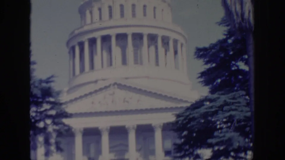 Sacramento Capitol exterior in 1966, showing the white dome, columns, and tree branches in a soft 8mm frame.