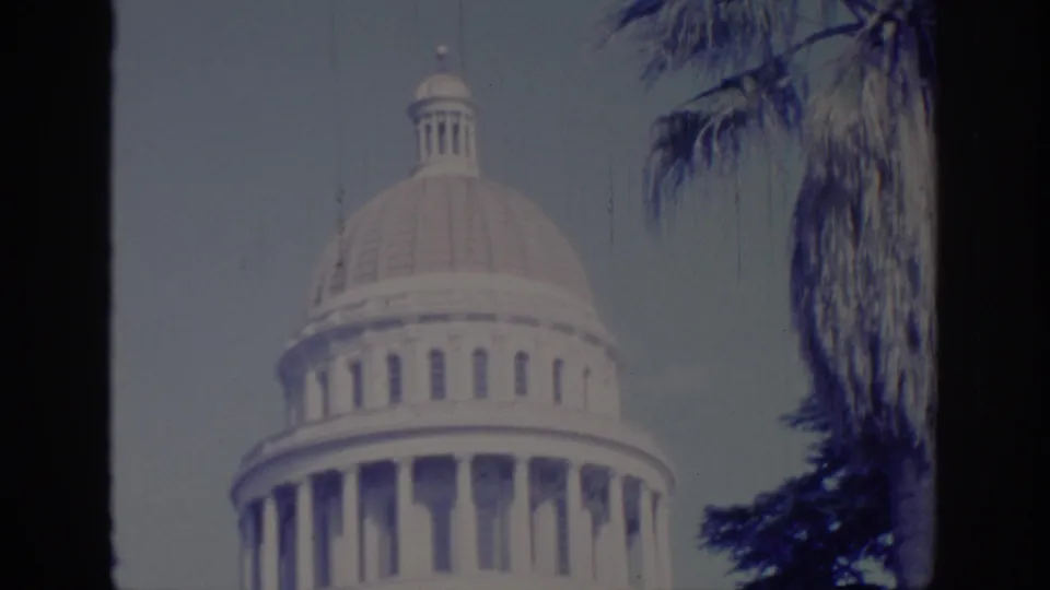 1966 Sacramento frame with the Capitol dome centered behind dark film borders and palm trees on the right.