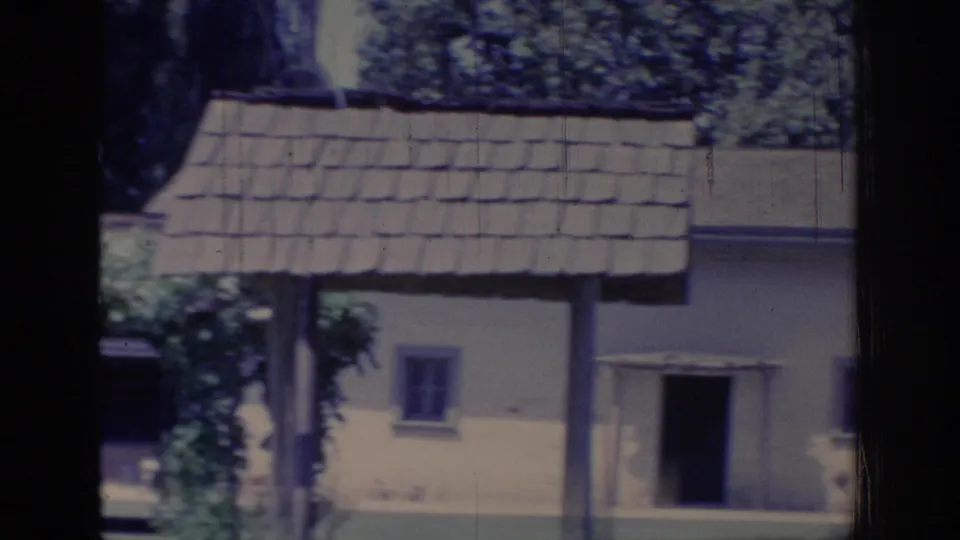 1966 Sacramento 8mm frame showing the cottage entrance, shingled arbor roof, small window, ivy, and dark gate shadow.