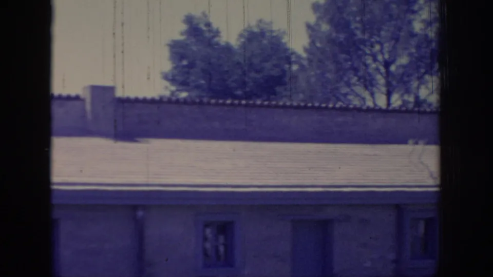 1966 Sacramento frame of a residential exterior with small windows, a doorway, tiled roof, garden wall, trees, and visible 8mm scratches.