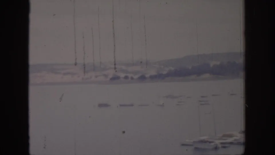 End frame of the 1966 Sacramento harbor view, with boats along the lower edge and distant hills across the water.
