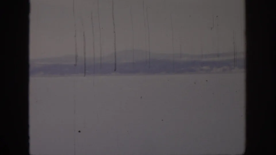 1966 8mm view of a hazy Sacramento-area waterfront, with distant hills and calm water partly obscured by film wear.