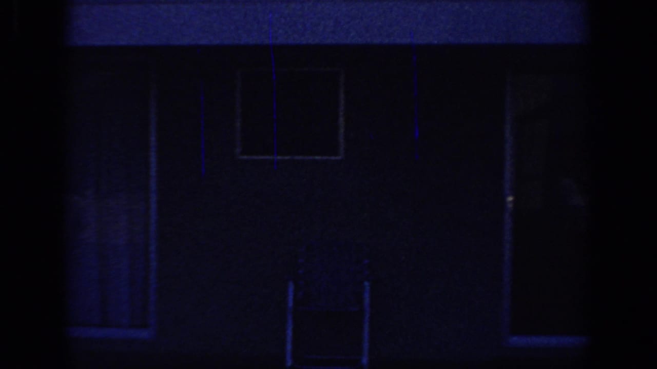 1966 Sacramento home-movie frame showing a dark house exterior with windows, deep blue cast, and a central vertical obstruction.