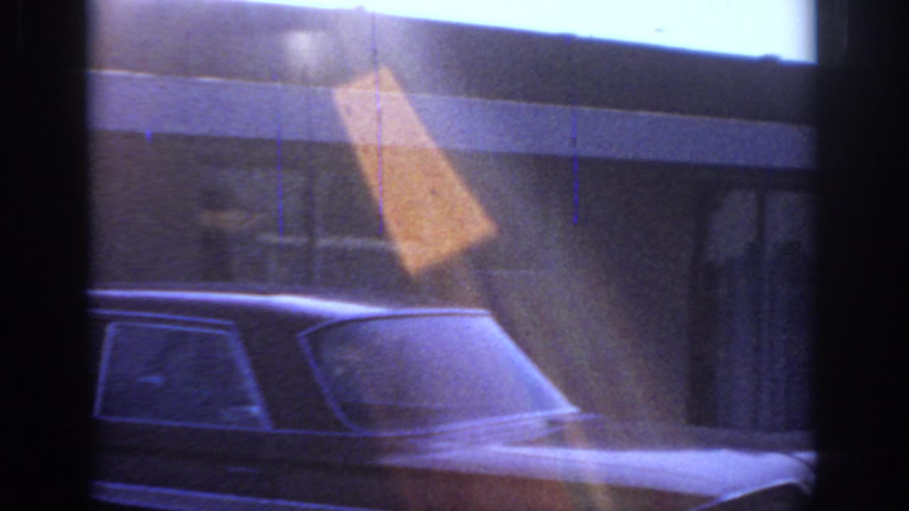 1966 Sacramento 8mm frame showing a shadowed vintage car, window mullions, and a low roadside building in fading light.
