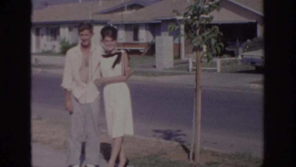 The couple remains posed on the Sacramento sidewalk, framed by a young street tree, houses, and the road behind them.