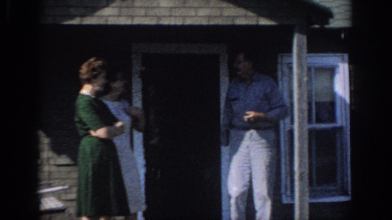 1966 Sacramento home-movie frame of two women and a man standing on a shaded brick house porch.