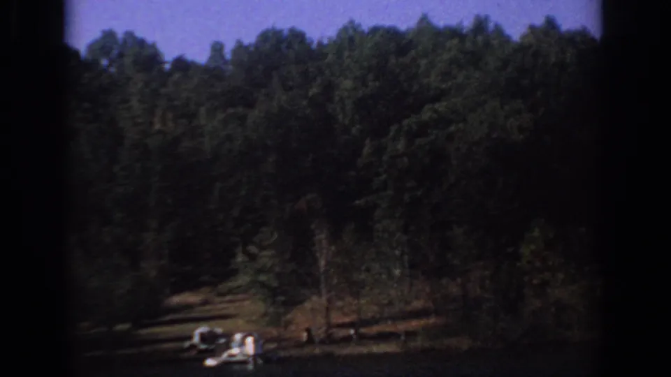 1966 Sacramento-area lakeside view with trees, open shoreline, and a small boat visible near the water.