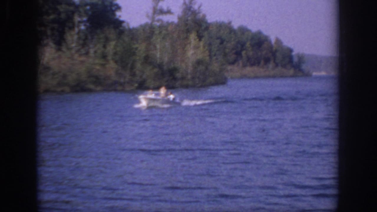 1966 Sacramento home-movie frame showing a small white motorboat moving across calm water near trees.