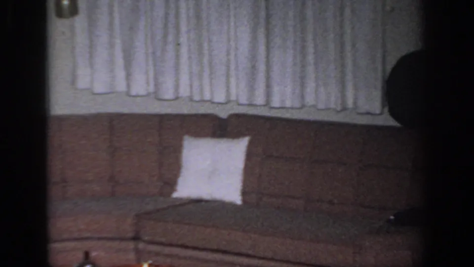 1966 Sacramento home interior showing a sectional sofa, white pillow, curtains, and shadowed wall area in soft 8mm color.