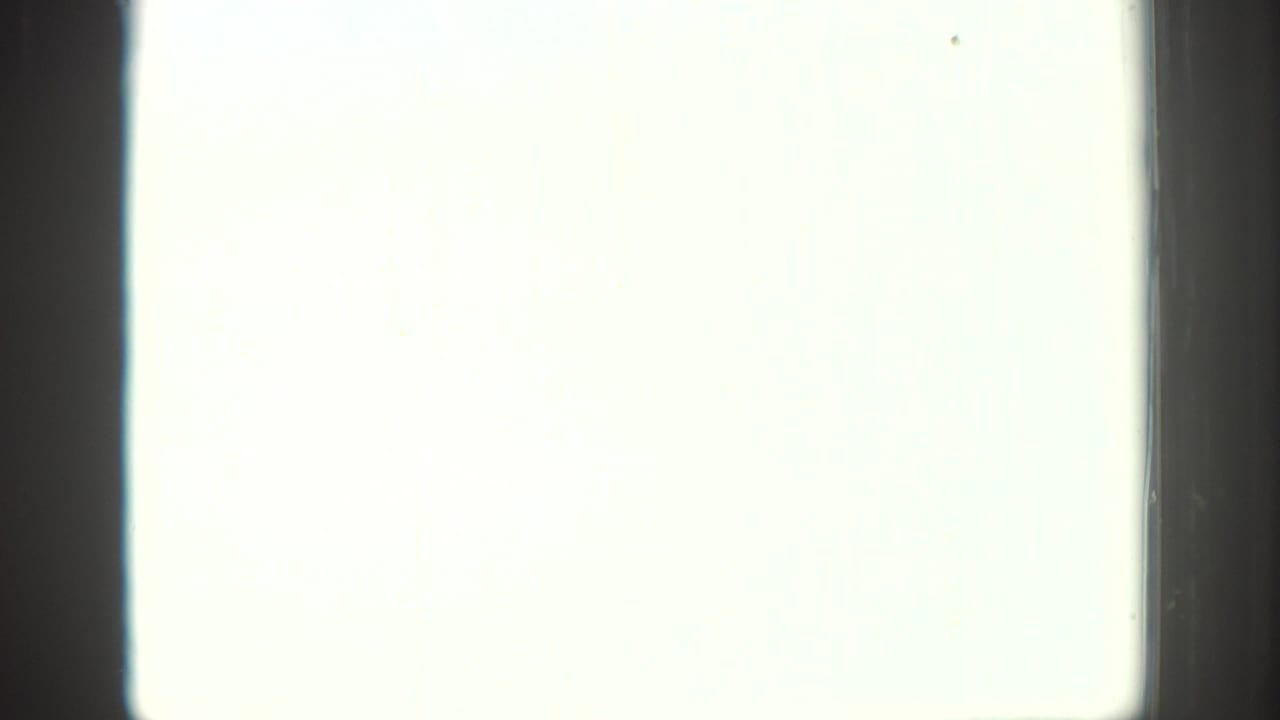 Overexposed 8mm frame section with a pale washed-out field, dark film edge, and minimal visible scene detail.
