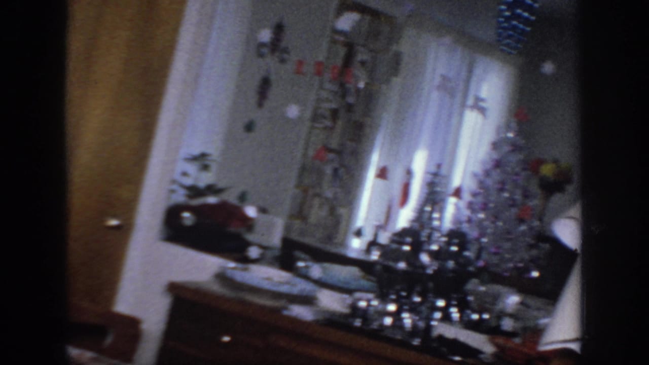 1966 Sacramento interior with white curtains, holiday tabletop decorations, lamp, and a silver tinsel tree during a slow pan.