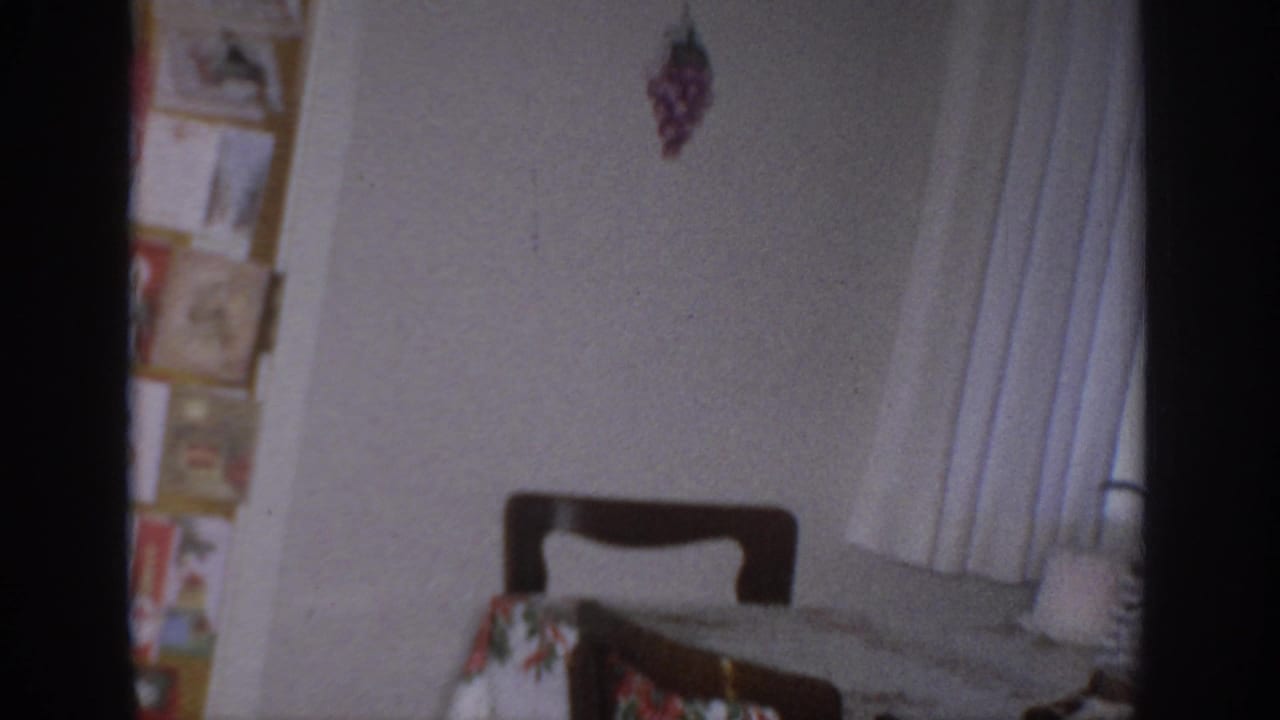 Room corner with a chair, curtain, wall pictures, and part of a holiday-decorated interior.