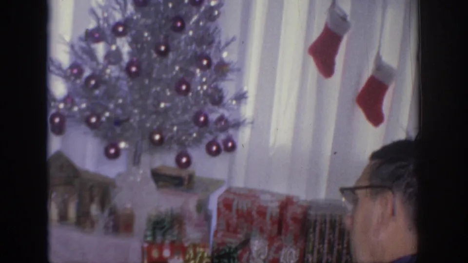 Silver aluminum Christmas tree with purple ornaments, red stockings, and wrapped gifts in a 1966 Sacramento home interior.